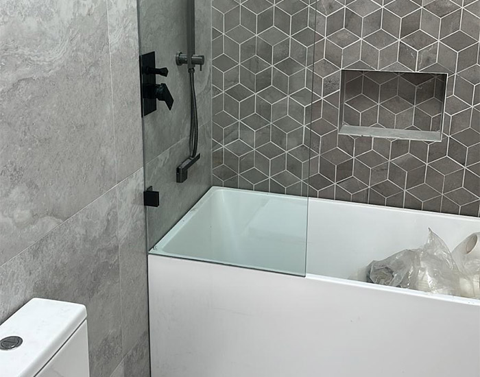 Custom glass bath screen over a white bathtub